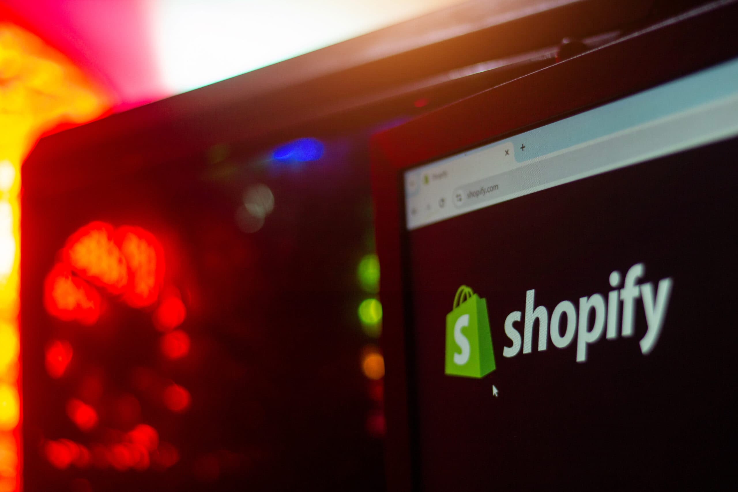 Computer screen showing the Shopify logo on the shopify.com website homepage.
